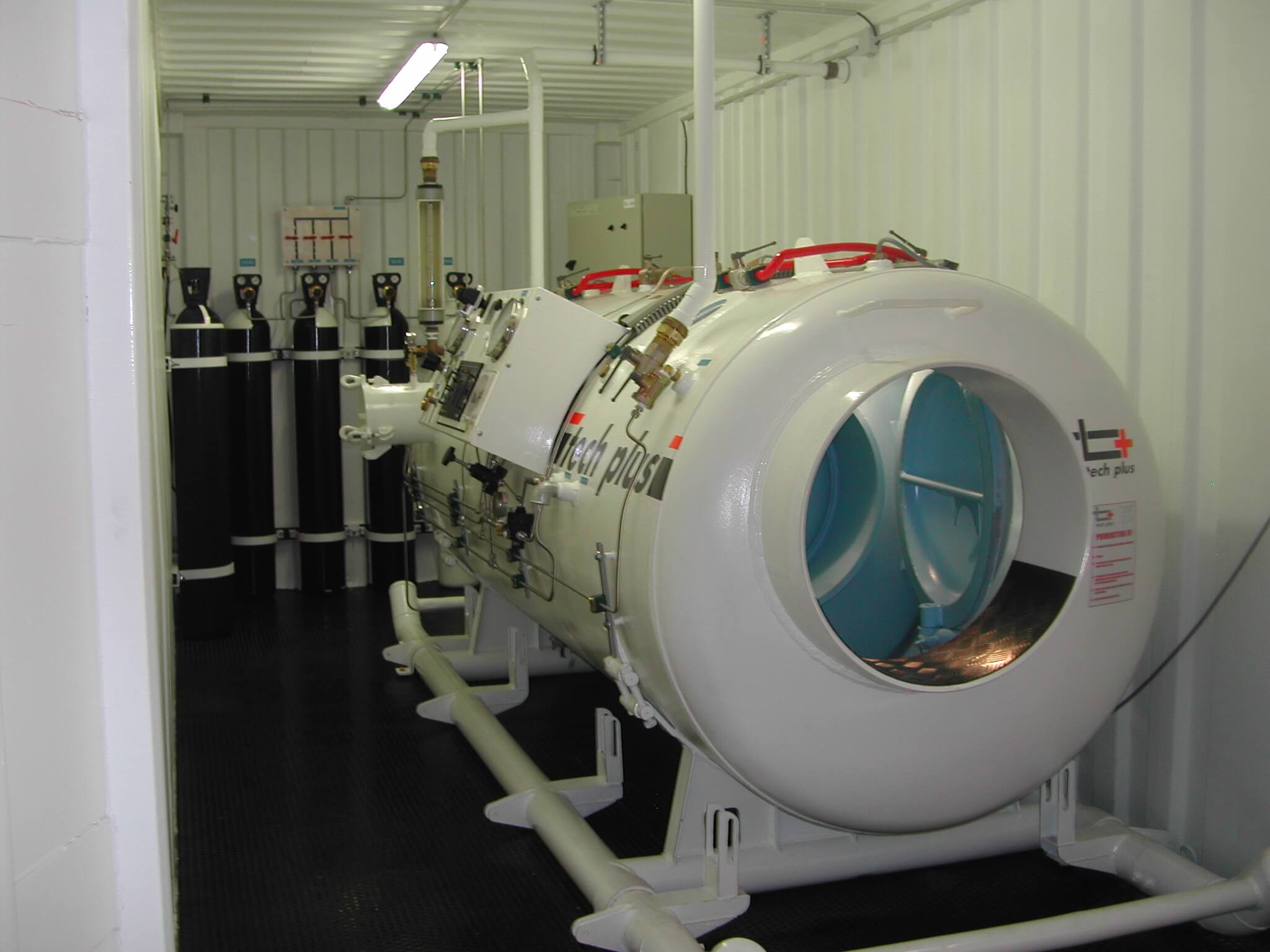 Caisson de décompression de plongée Tech Plus installé dans un conteneur, avec ses racks de bouteilles de gaz