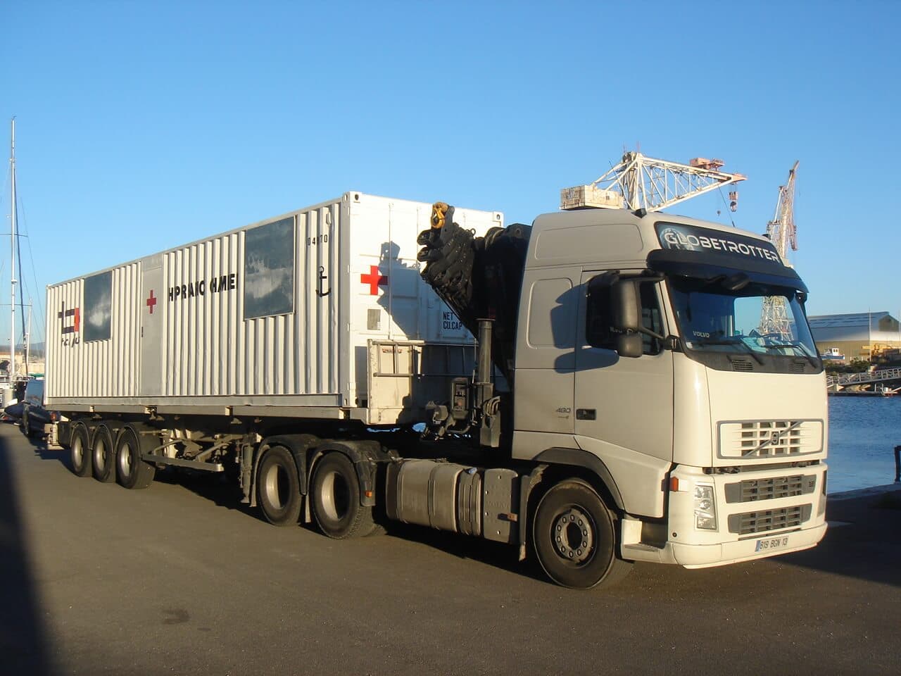 Caisson hyperbare Tech Plus en conteneur, marqué de croix rouges, sur une semi-remorque à quai