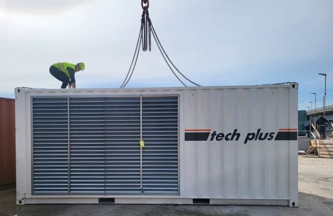Conteneur Tech Plus à grilles de ventilation en cours d'élingage, un opérateur sur le toit